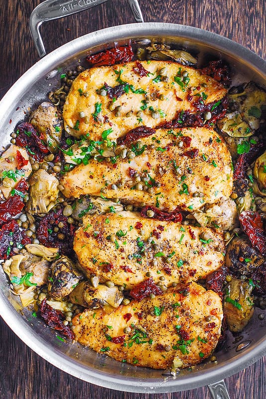 Mediterranean Chicken with Sun-Dried Tomatoes, Artichokes, and Capers - in a stainless steel skillet.