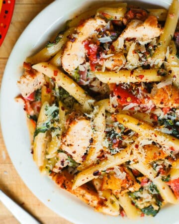 Chicken and Bacon Pasta with Spinach and Tomatoes in Garlic Cream Sauce - on a white plate.