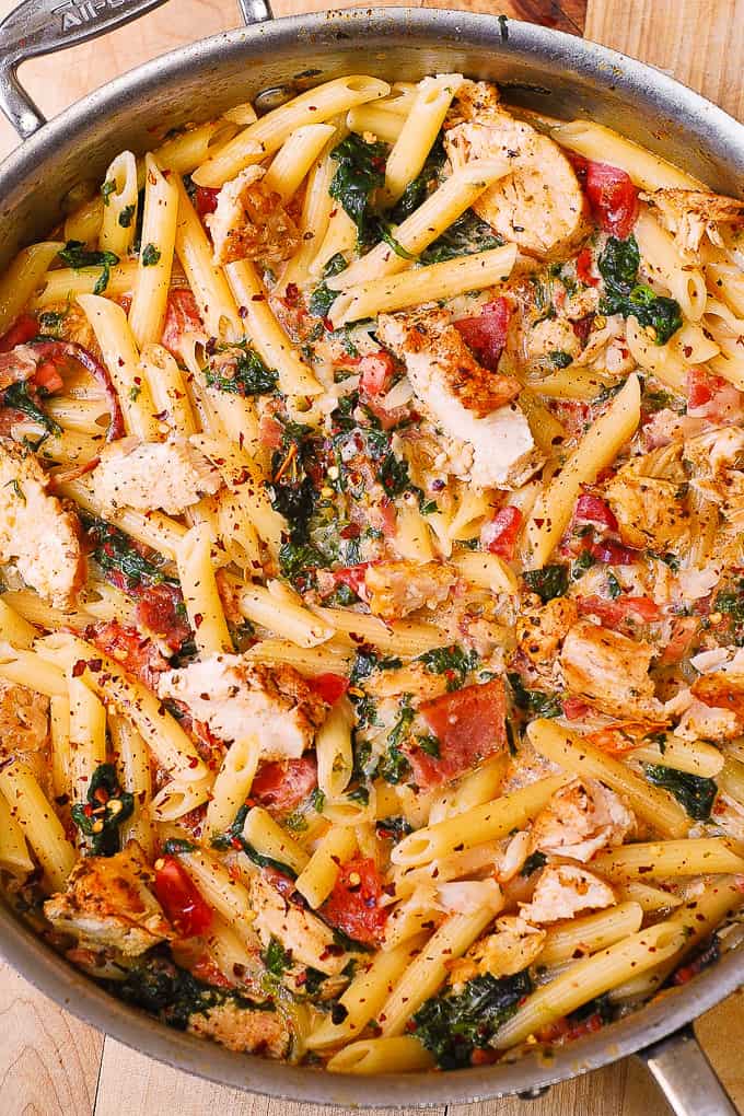 chicken bacon pasta with tomatoes, spinach in a stainless steel pan