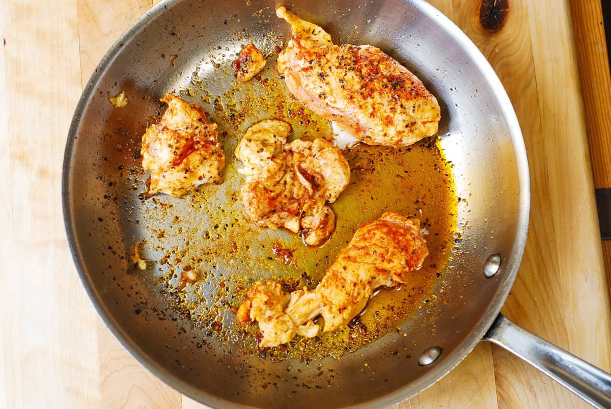 Cooked chicken in a stainless steel skillet.