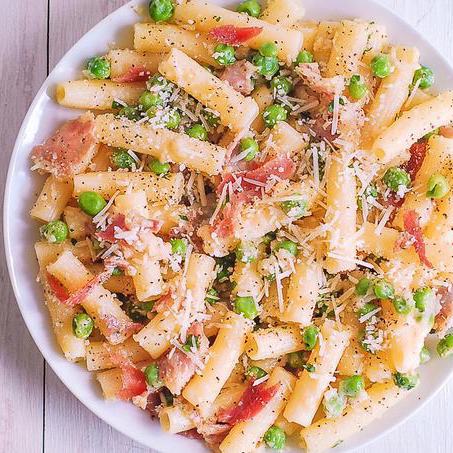 prosciutto pasta with peas on a white plate