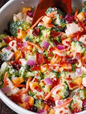 Broccoli and Cauliflower Salad with Cheddar Cheese, Bacon, Cranberries, Carrots, Red Onions - in a white bowl.