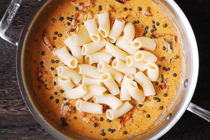 creamy mozzarella cheese sauce with capers and rigatoni pasta in a large skillet