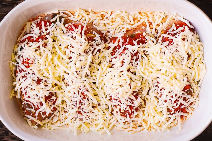 Mozzarella cheese, tomato sauce, mushrooms on top of chicken breasts in a casserole dish