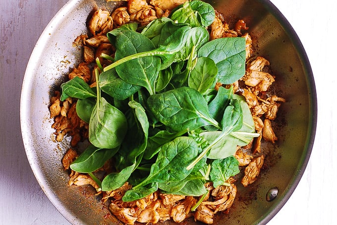 cooked chicken with spinach in a skillet