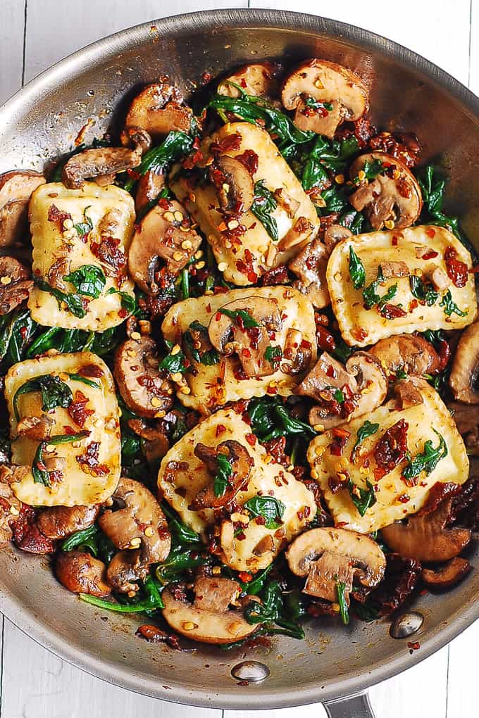mushroom ravioli with spinach in a stainless steel skillet