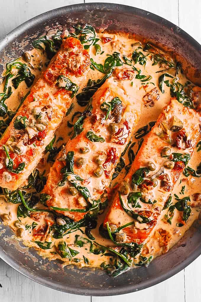 Creamy Tuscan Salmon with Spinach, Artichokes, Garlic, and Capers in a stainless steel skillet