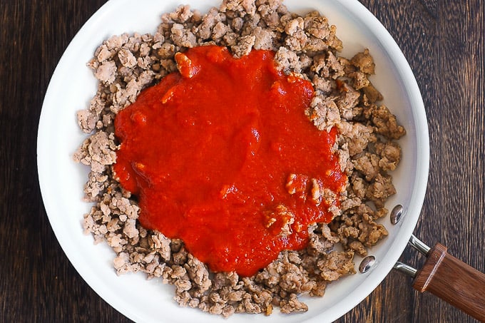tomato sauce and cooked Italian sausage in a skillet
