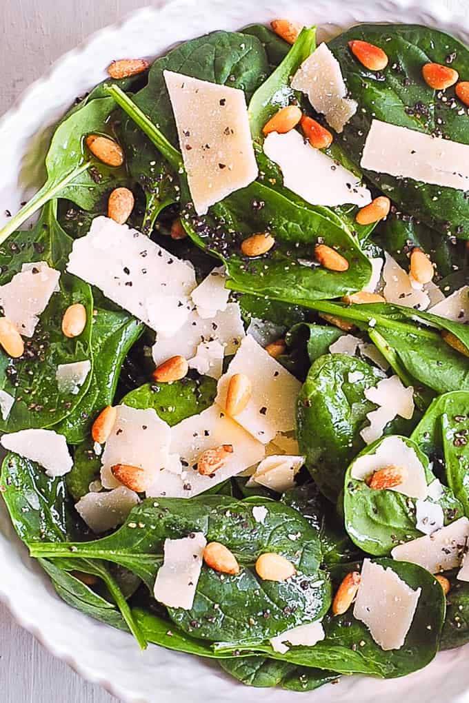 simple spinach salad with pine nuts and shaved parmesan cheese