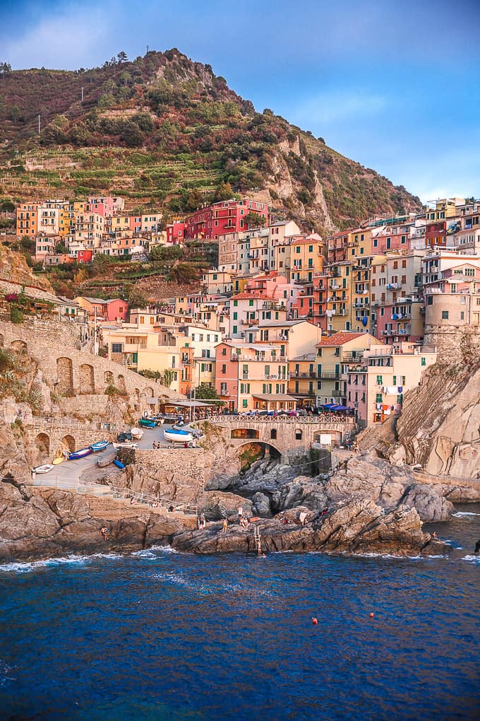 Colorful buildings and a mountain overlooking the water in Manarola, Italy