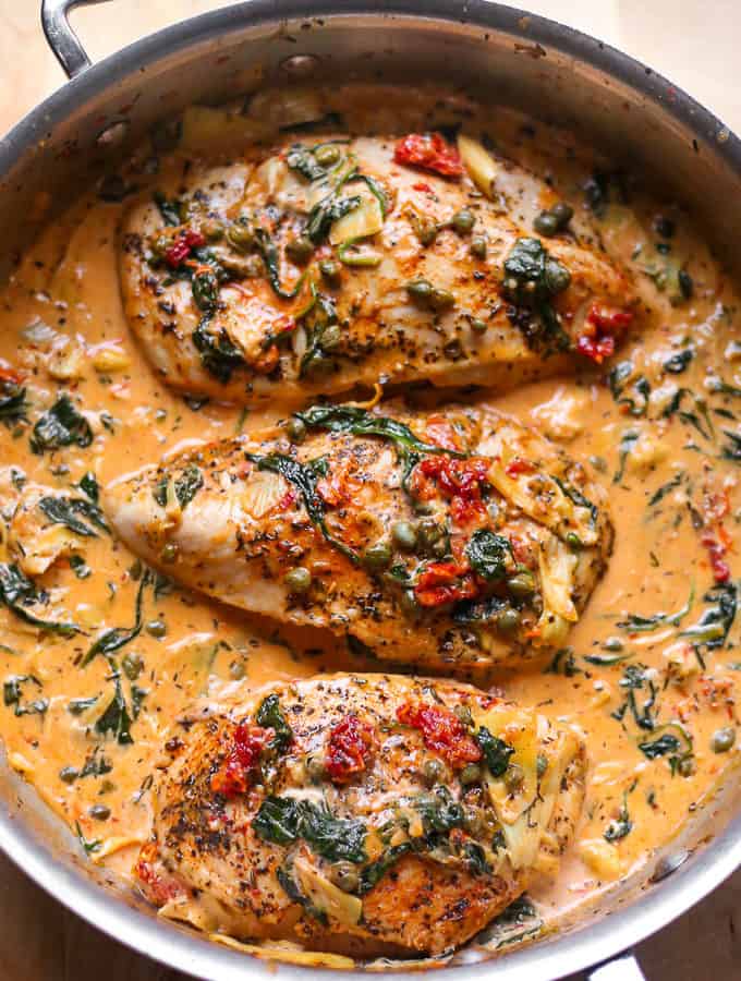 Creamy Tuscan Chicken with Spinach, Artichokes, Sun-Dried tomatoes in a stainless steel skillet