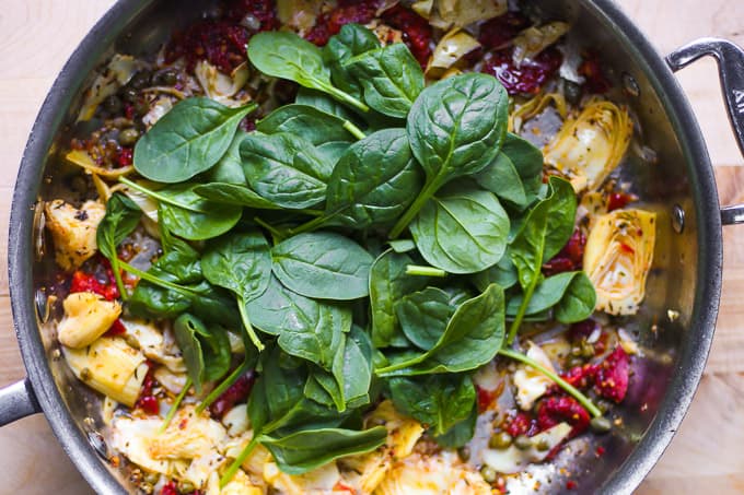 Spinach, artichokes, sun-dried tomatoes, capers in a skillet