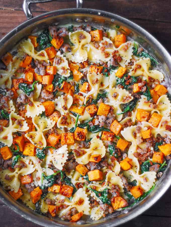 Creamy Butternut Squash Pasta with Sausage and Spinach and creamy Parmesan Sauce in a stainless steel pan