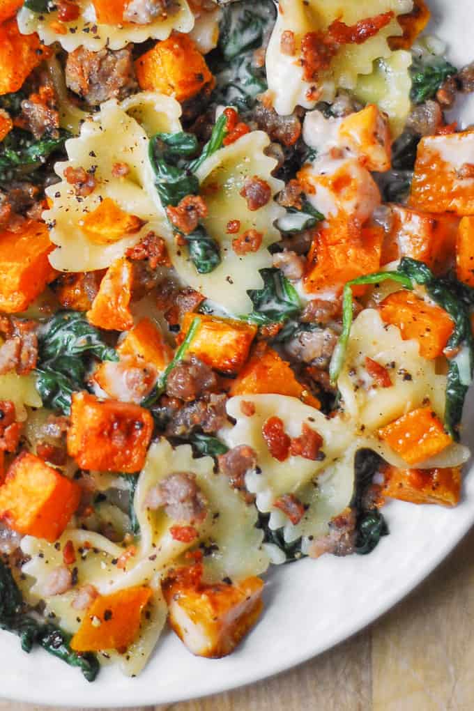 Creamy Butternut Squash Pasta with Sausage and Spinach on a white plate (close-up)
