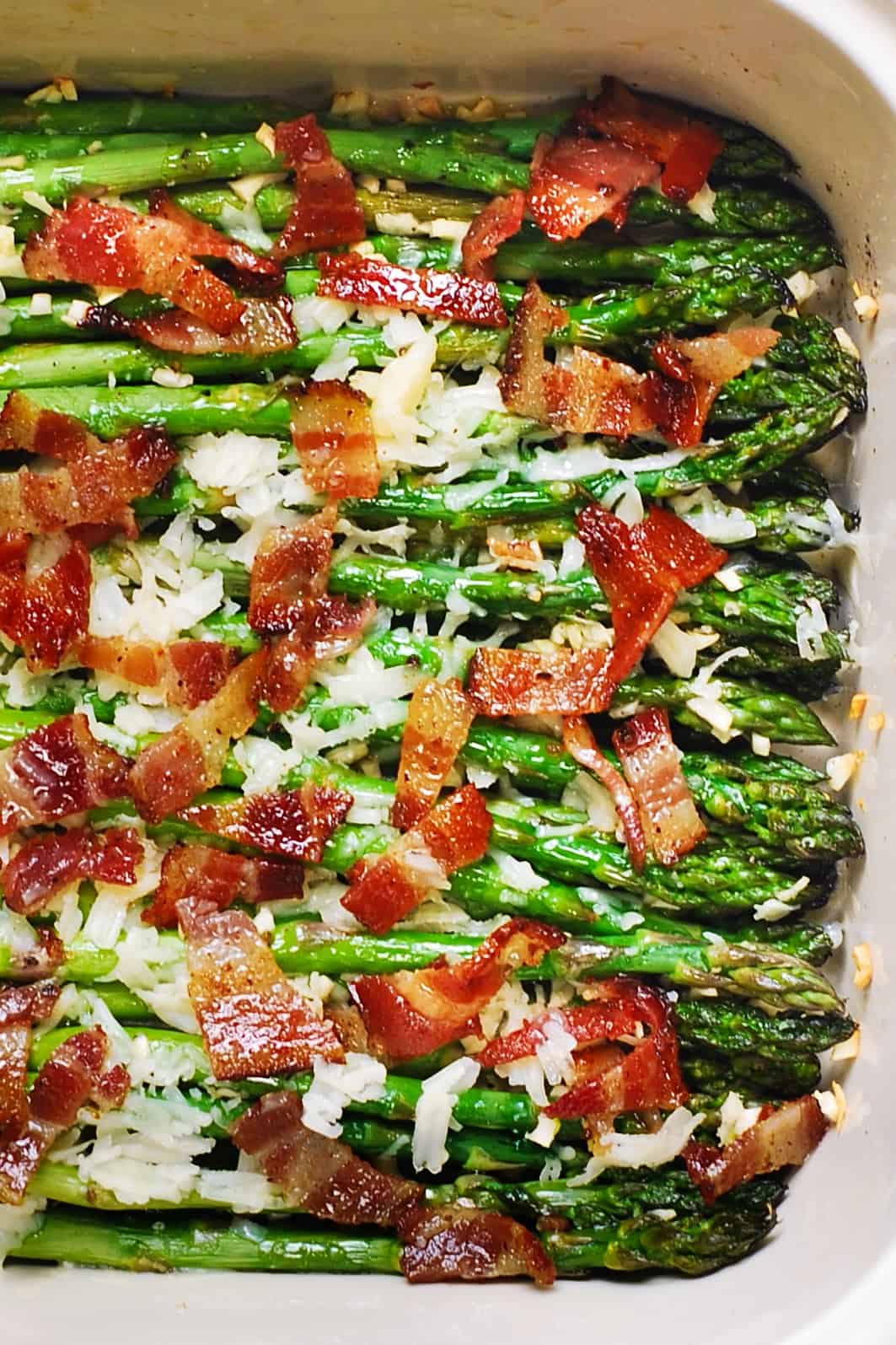 close-up of Cheesy Baked Asparagus with Gruyere cheese, Garlic, and Bacon in a baking dish