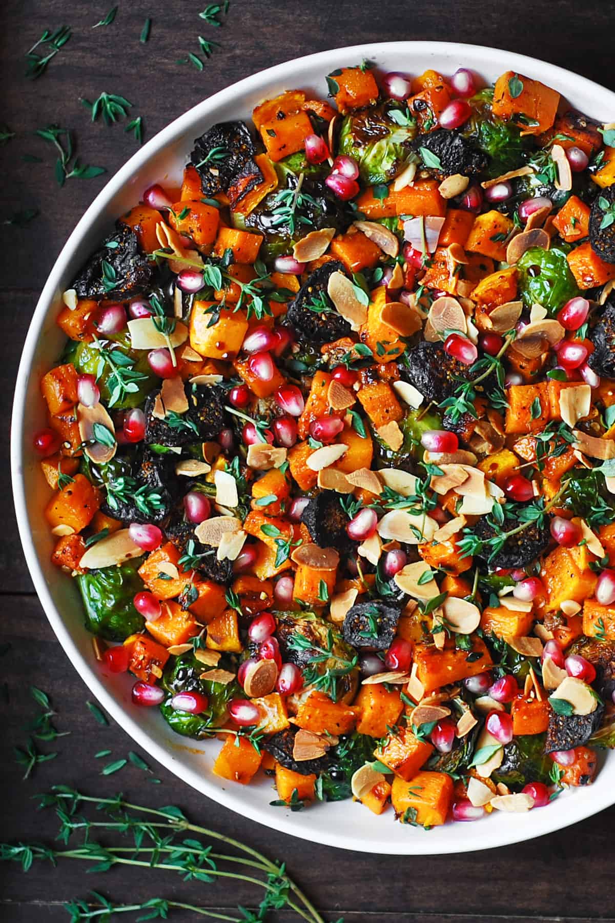 Roasted Brussels Sprouts Salad with Figs, Almonds, Butternut Squash, and Pomegranate Seeds in a white bowl