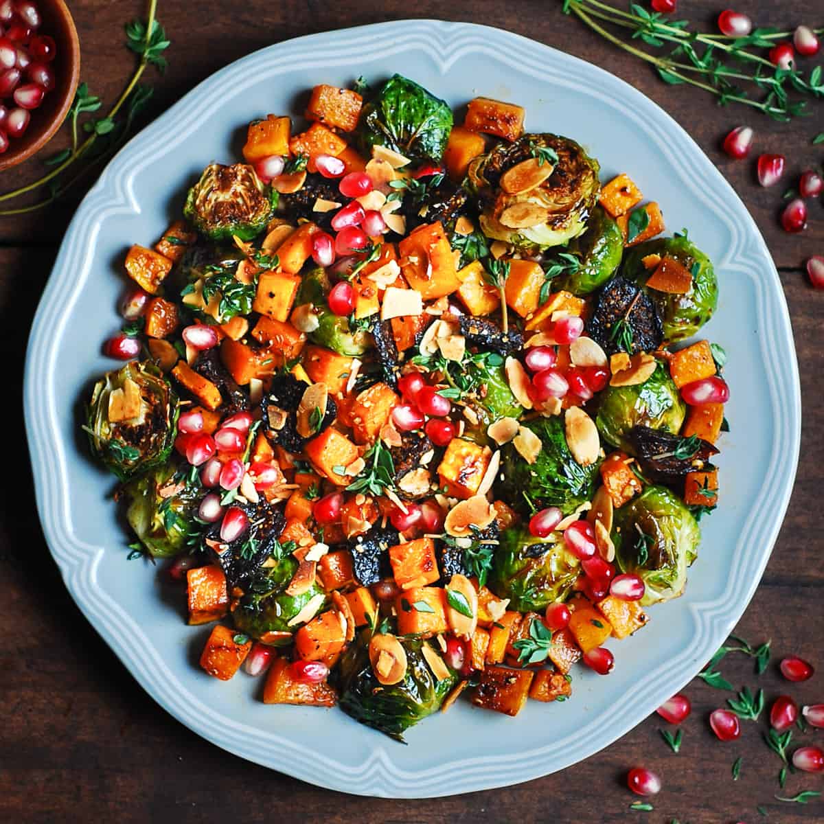 Roasted Brussels Sprouts Salad with Figs, Almonds, Butternut Squash, and Pomegranate Seeds on a gray plate