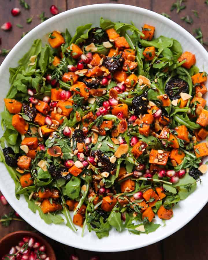 Fall Salad with Butternut Squash, Arugula, Dried Figs, and Almonds in a white bowl