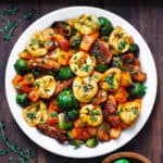 seared chicken, tortellini with roasted butternut squash and brussels sprouts on a white plate