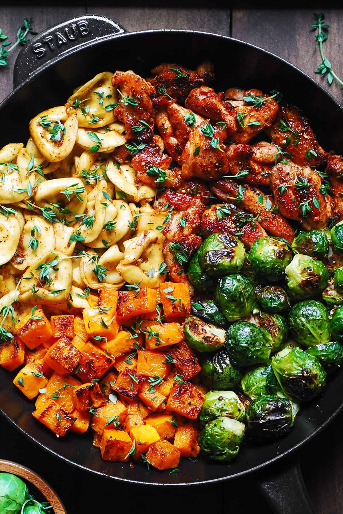 seared chicken, tortellini with roasted butternut squash and brussels sprouts in a cast-iron pan