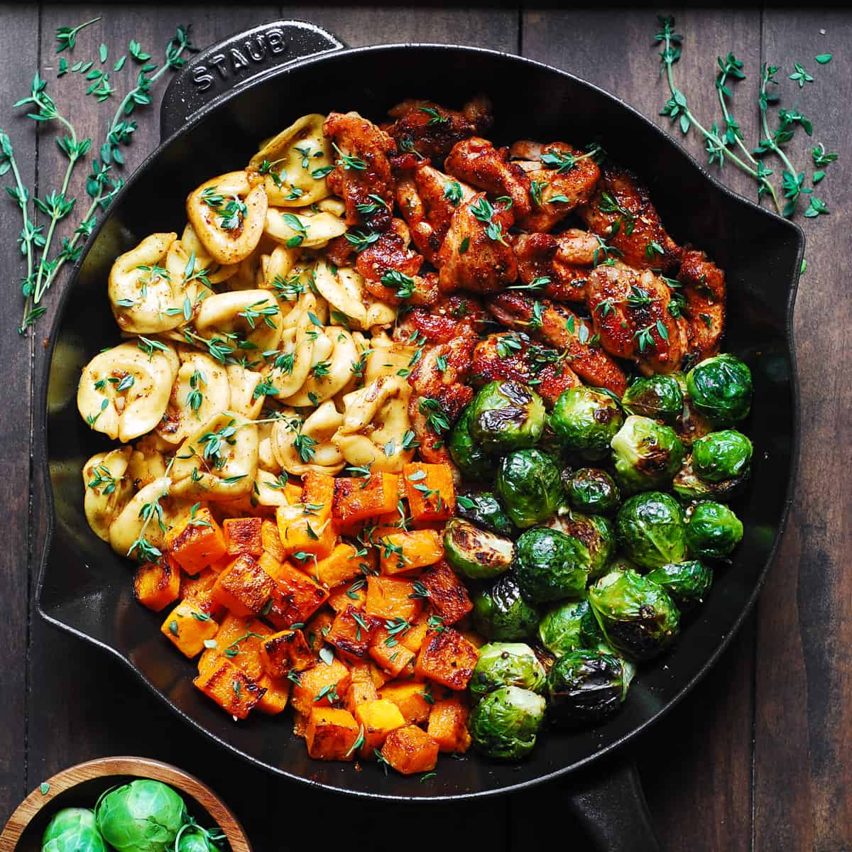 seared chicken, tortellini with roasted butternut squash and brussels sprouts in a cast-iron skillet