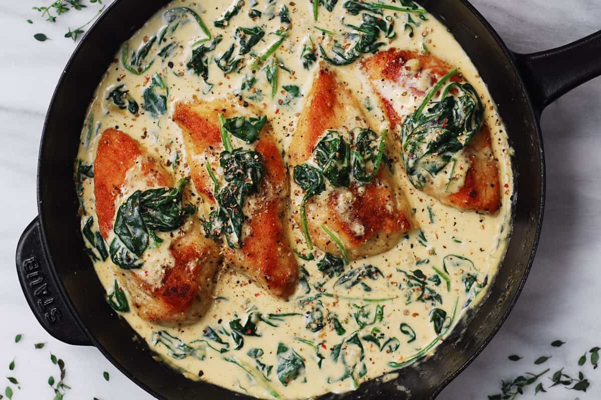chicken with creamy spinach sauce in a cast-iron skillet
