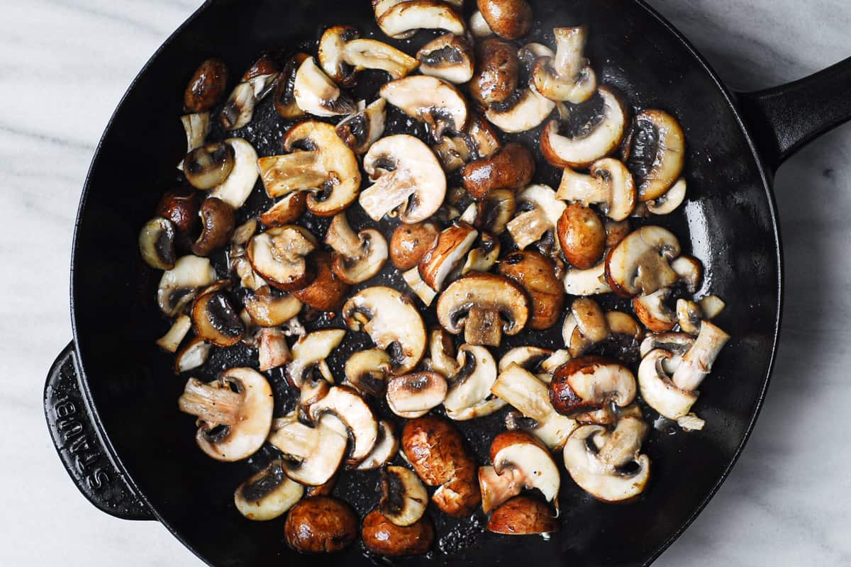 cooked sliced mushrooms in a cast-iron skillet