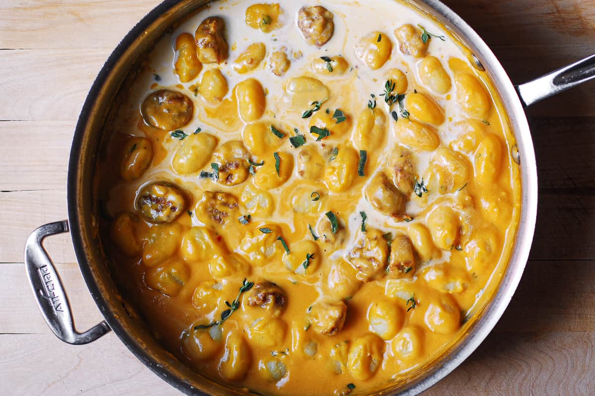 creamy butternut squash sauce with gnocchi and sausage in a stainless steel pan