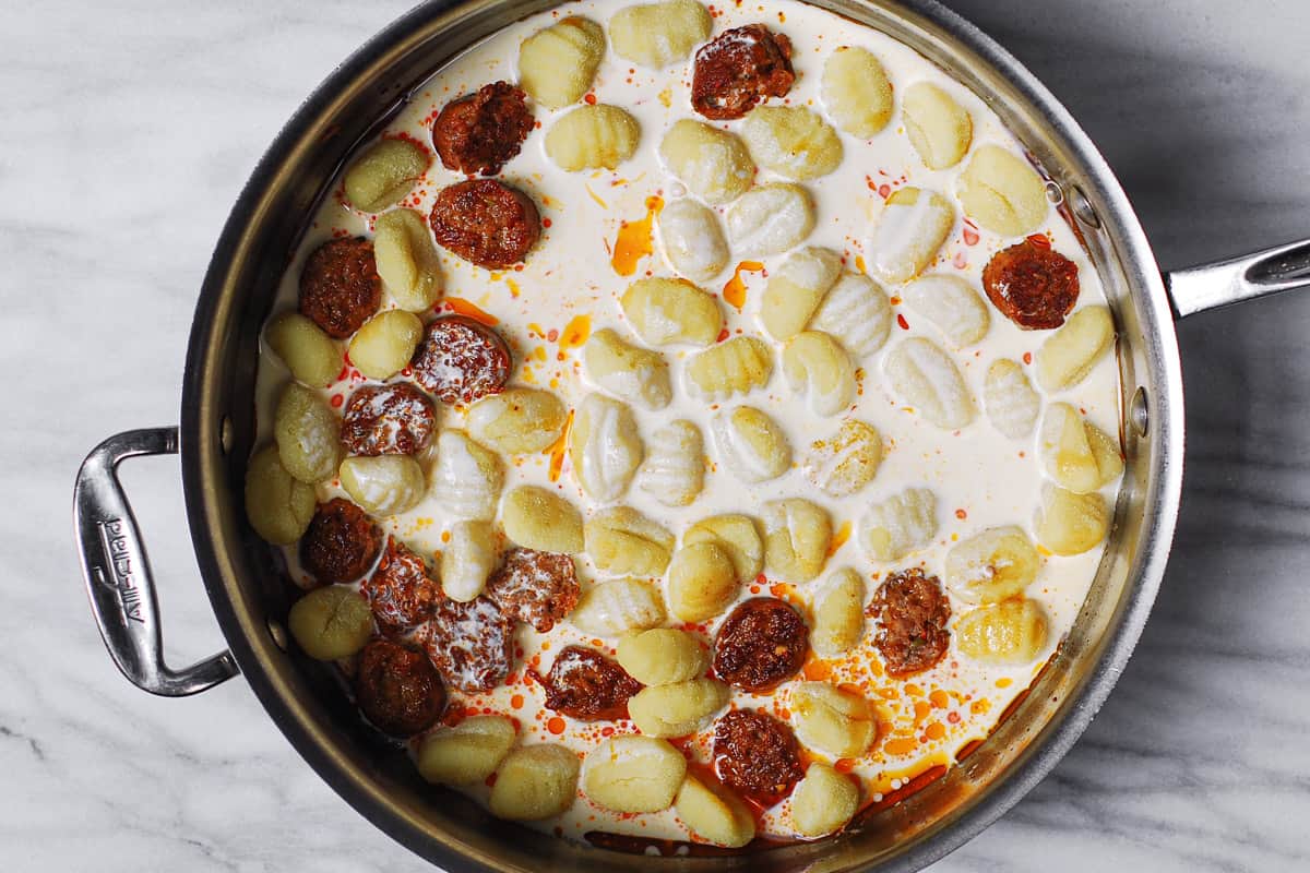 gnocchi, sausage, and cream in a stainless steel pan