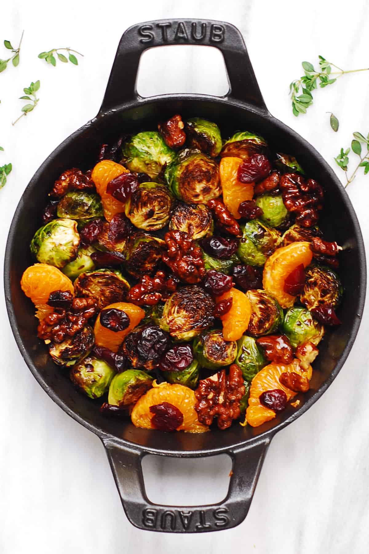 mandarin orange salad with dried cranberries, walnuts, roasted Brussels sprouts, and balsamic glaze in a cast-iron pan