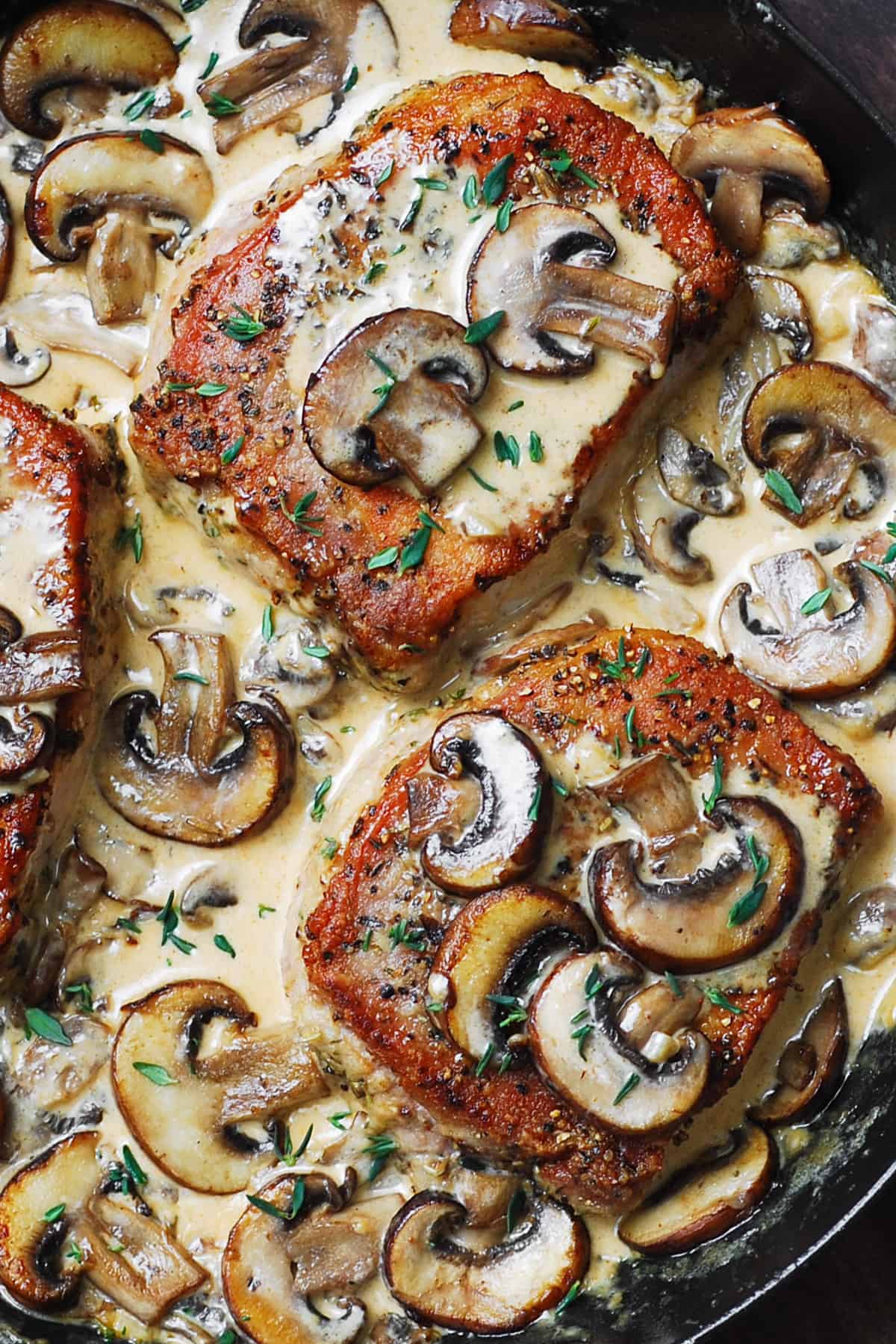 close-up of creamy pork chops with mushroom sauce in a cast-iron skillet