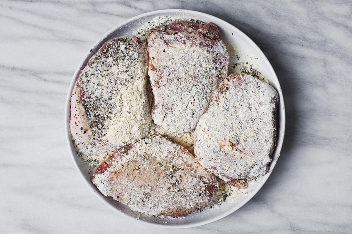 seasoned pork chops (and dredged in flour) on a plate