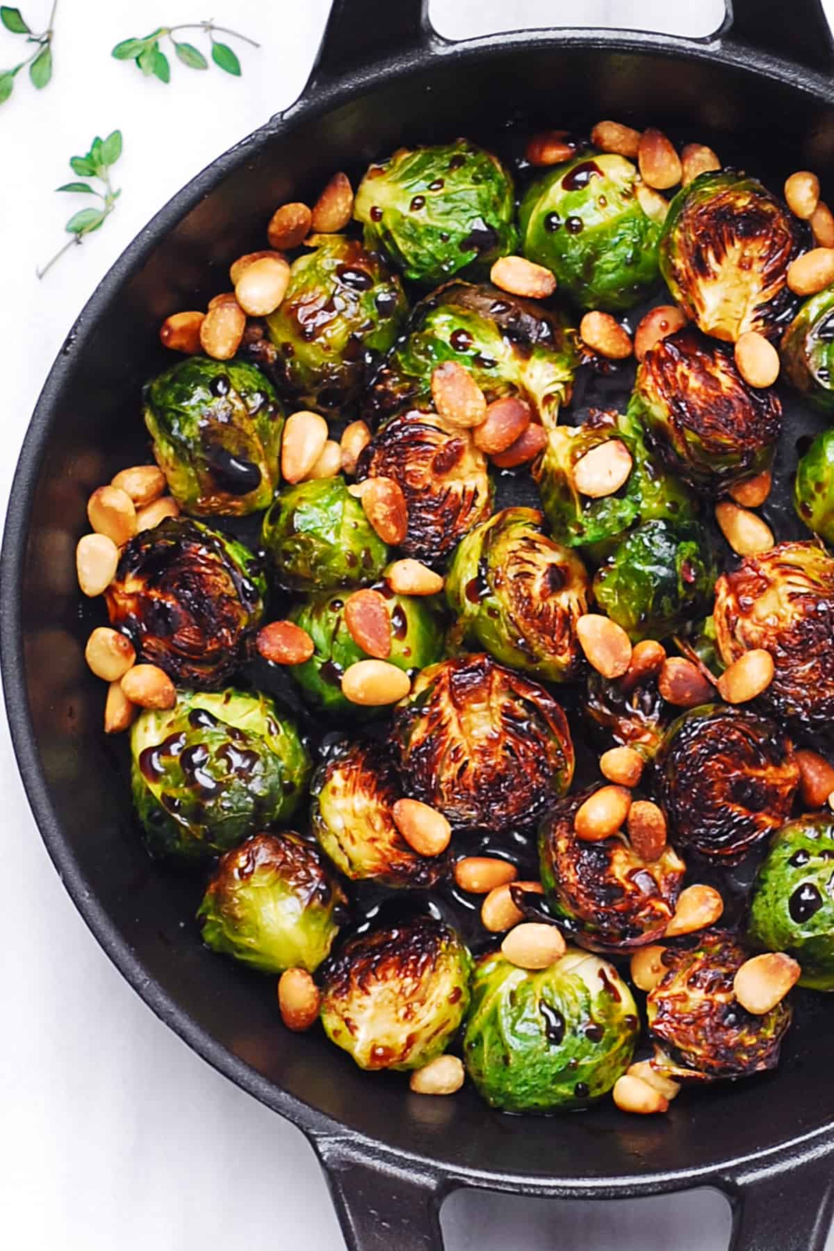 Roasted Brussels Sprouts with Balsamic Glaze and Pine Nuts in a cast-iron pan