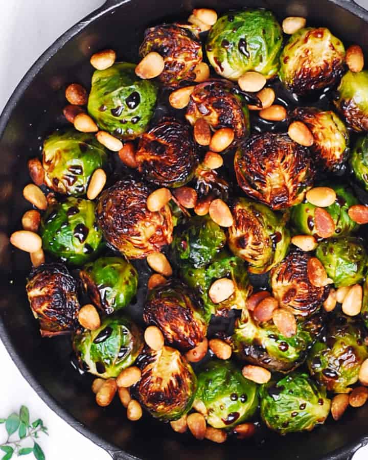 Brussels Sprouts with Balsamic Glaze and Pine Nuts in a cast-iron pan