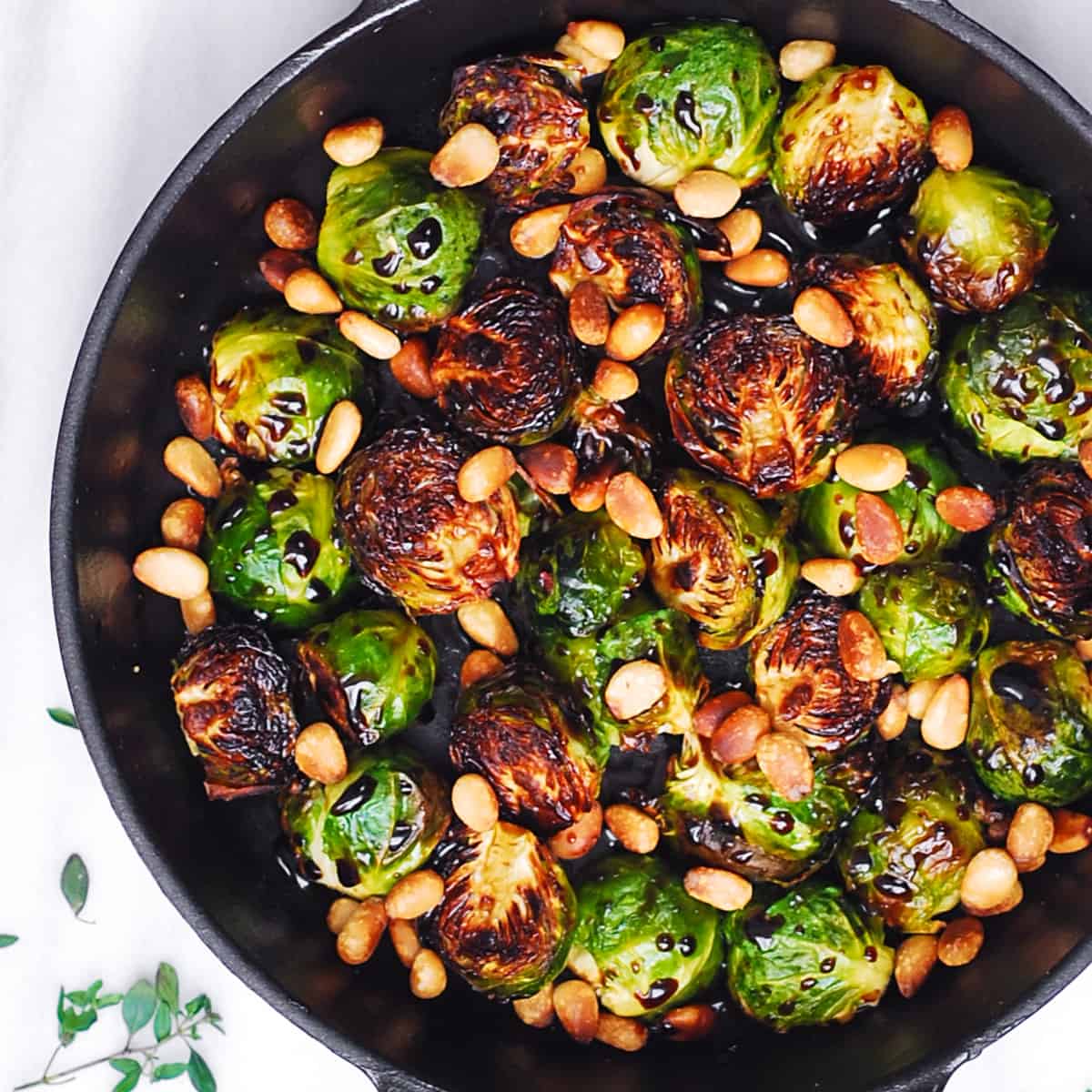 Brussels Sprouts with Balsamic Glaze and Pine Nuts in a cast-iron pan