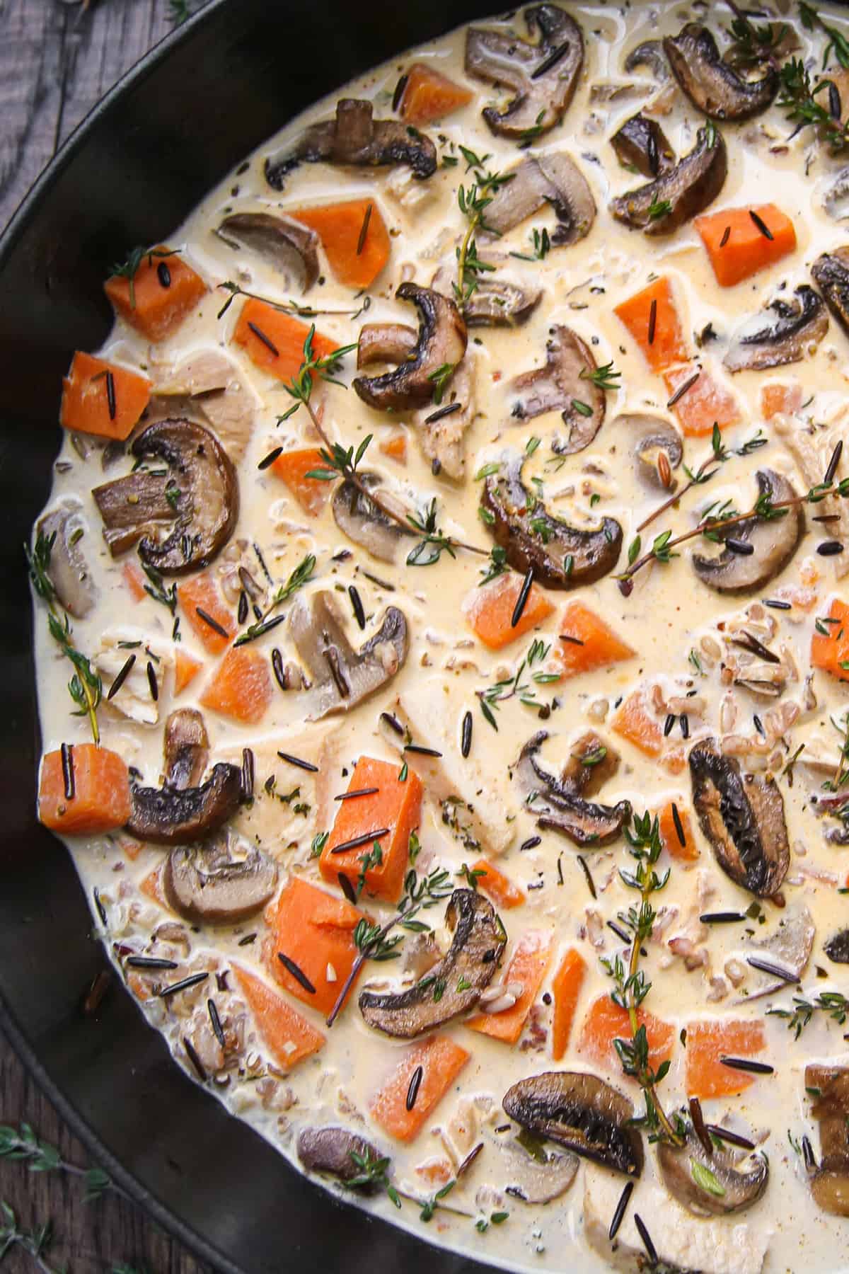creamy chicken wild rice soup with mushrooms and sweet potatoes in a cast iron pan