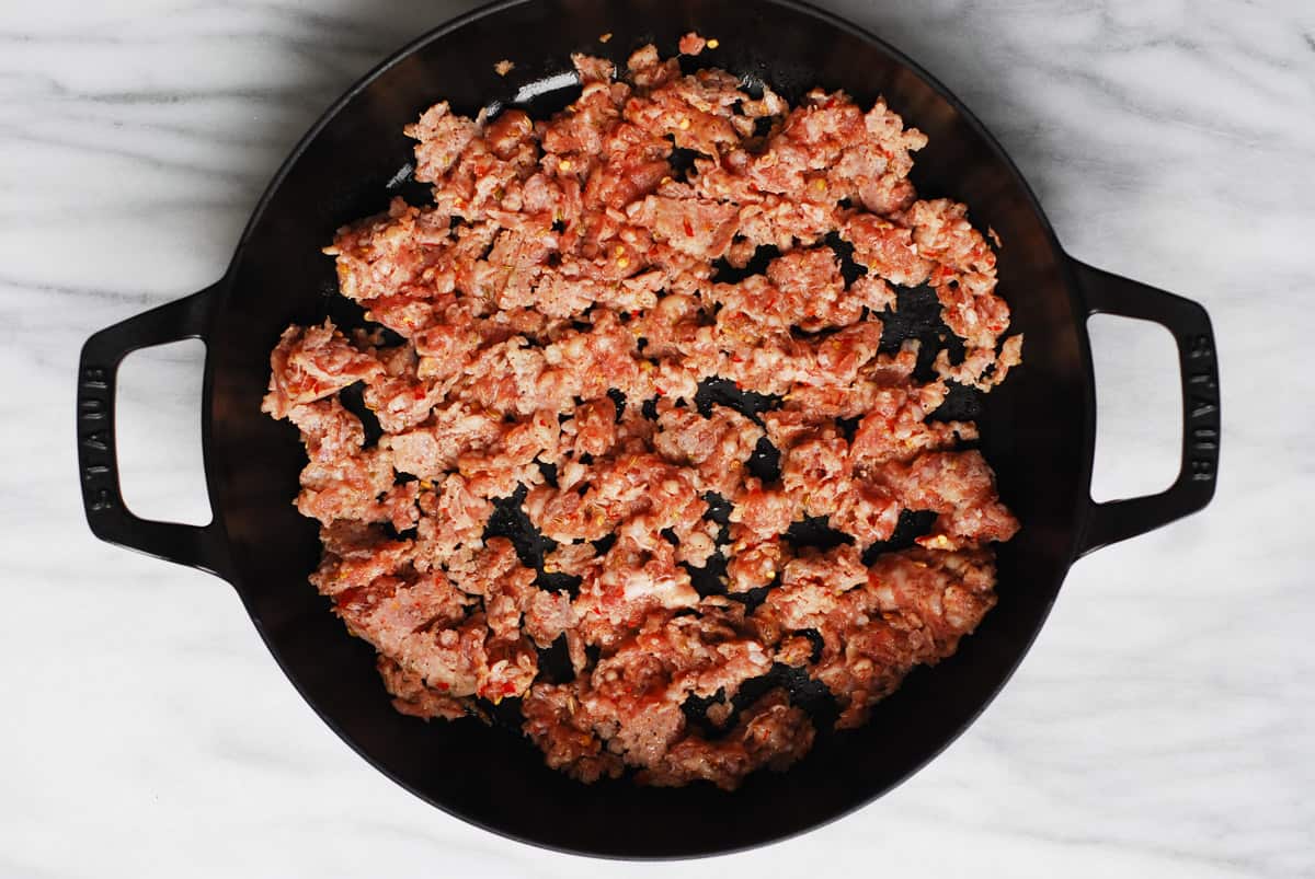 raw crumbled Italian sausage in a cast-iron pan