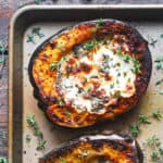 stuffed acorn squash with spinach and cheese on a baking sheet