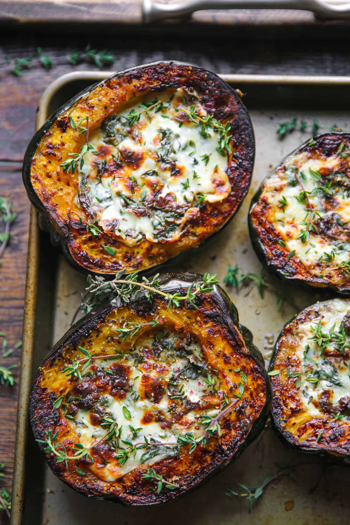 roasted acorn squash halves stuffed with spinach and cheese mixture on a baking sheet