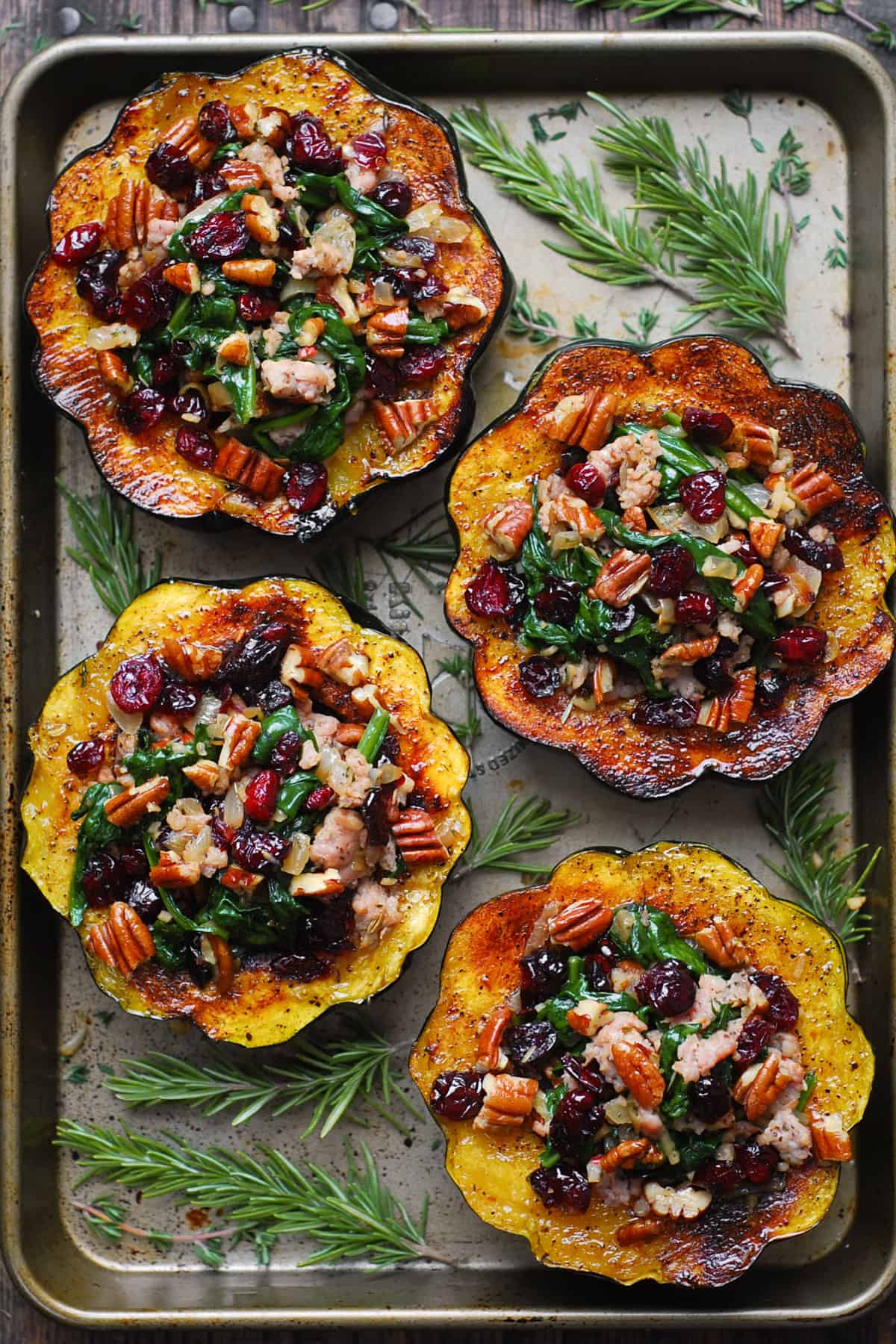 stuffed acorn squash with sausage, dried cranberries, spinach, pecans on a baking sheet