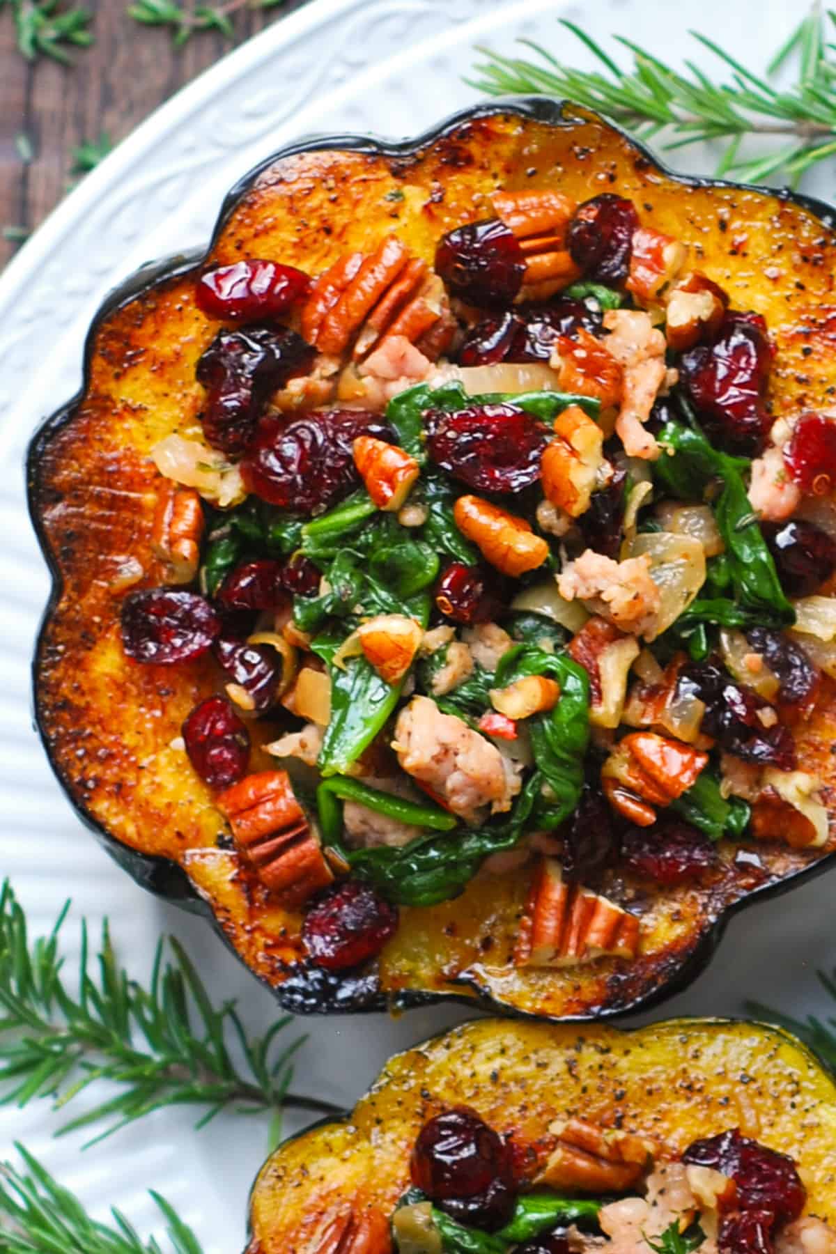 Close-up of acorn pumpkin stuffed with sausage, spinach, dried cranberries and pecans on a white plate