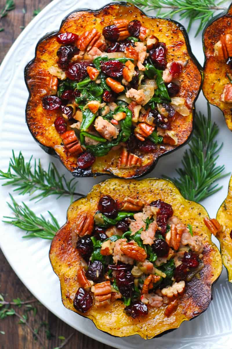 stuffed acorn squash with sausage, dried cranberries, spinach, pecans on a white plate