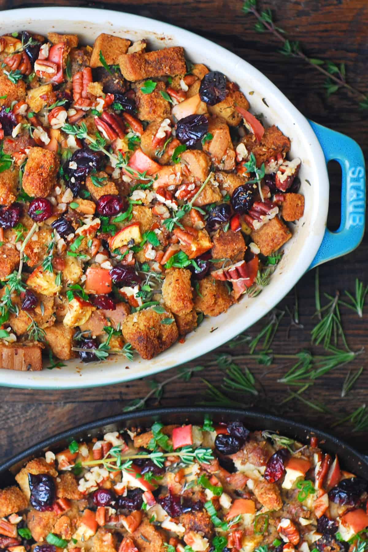 Christmas sausage stuffing with apples, cranberries, and pecans in two oval baking dishes