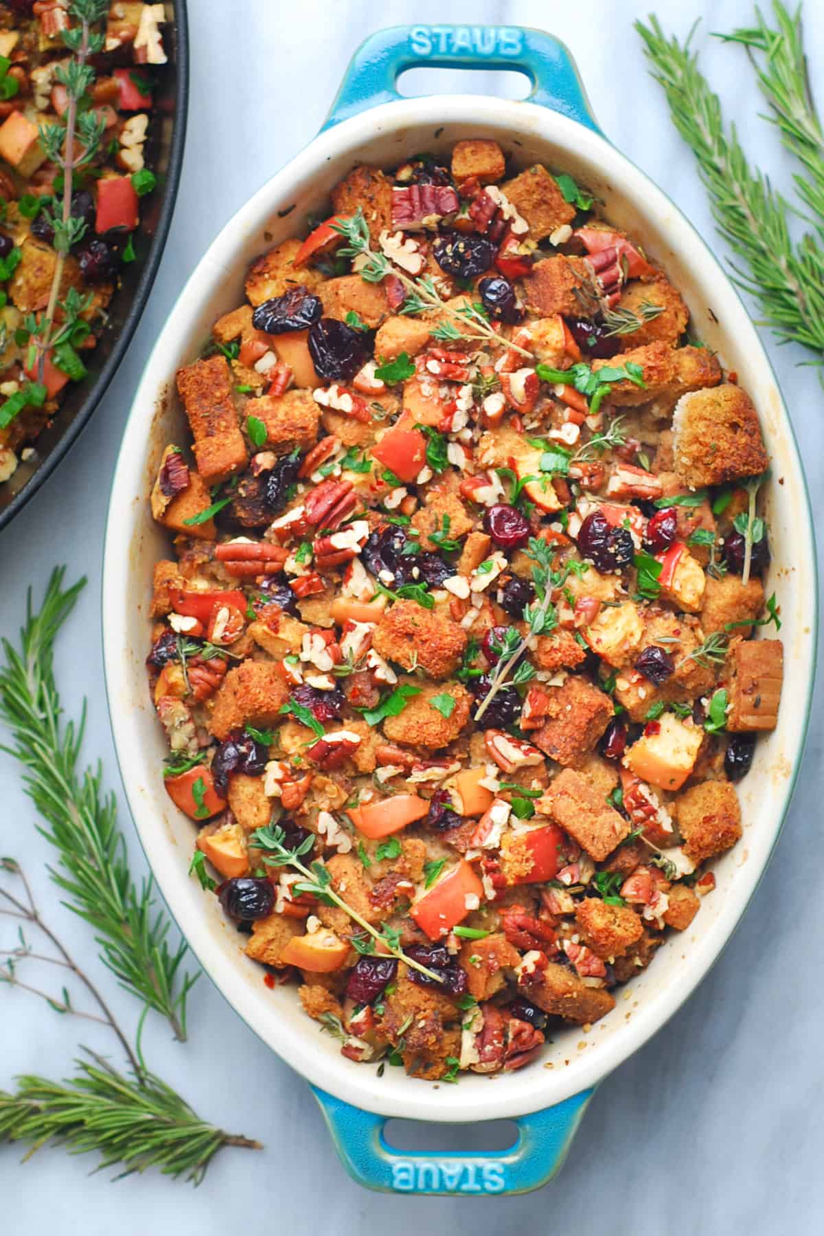 sausage stuffing with apples, cranberries, and pecans in an oval baking dish