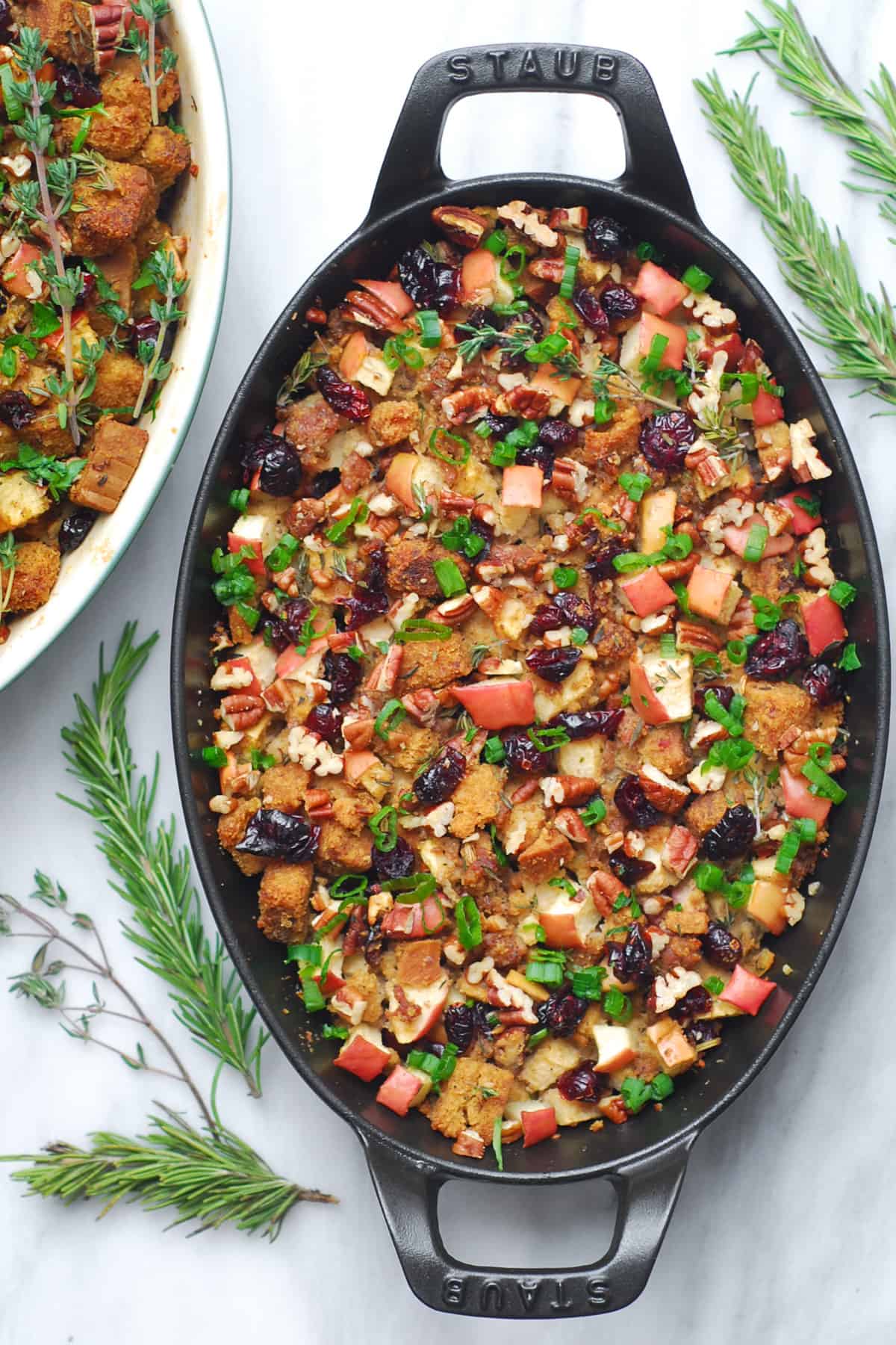 Thanksgiving sausage stuffing with apples, cranberries, and pecans in a cast iron oval dish