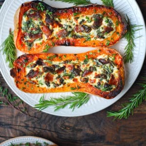 stuffed butternut squash with spinach, bacon, and cheese on a white plate