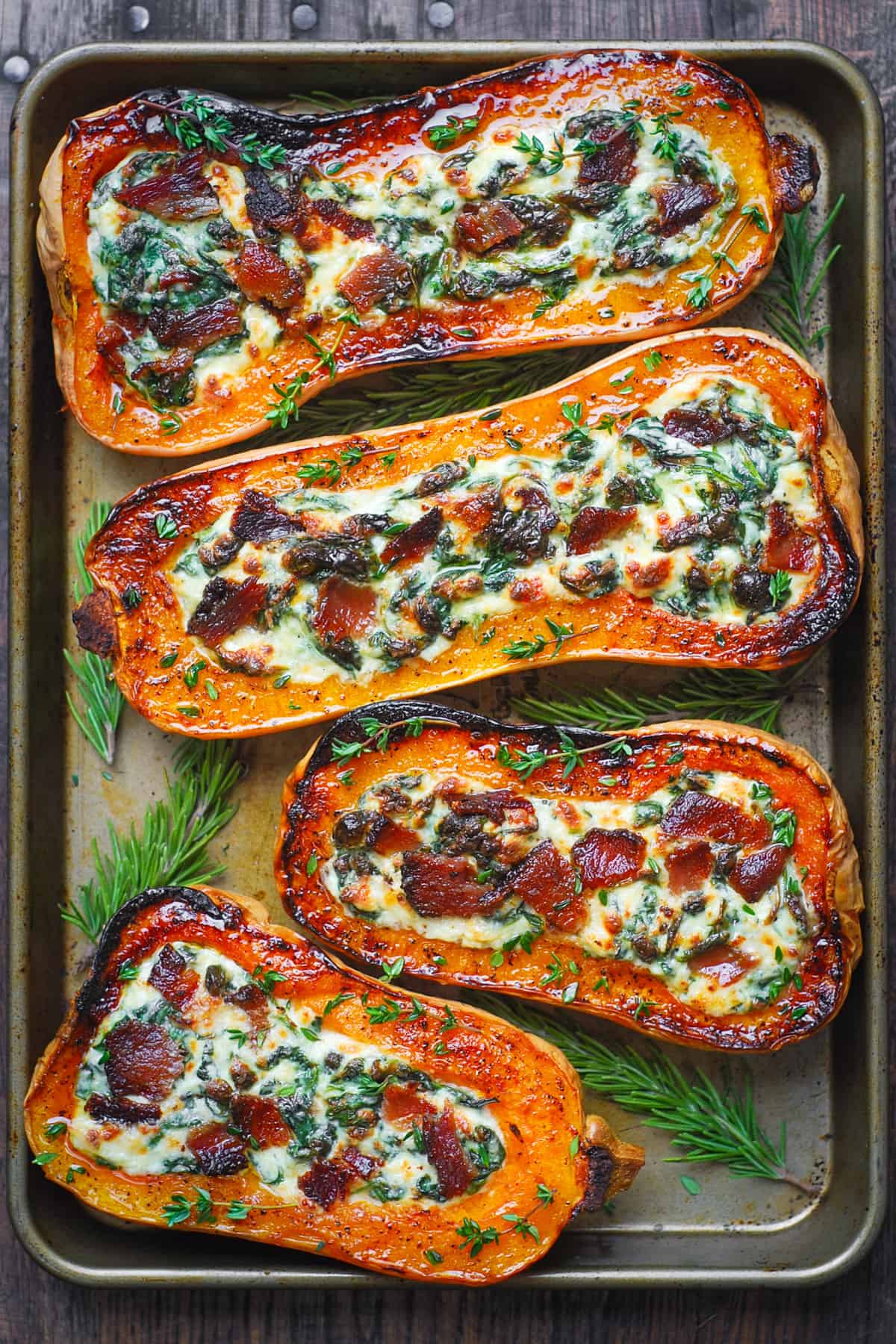 stuffed butternut squash with spinach, bacon, and cheese on a baking sheet