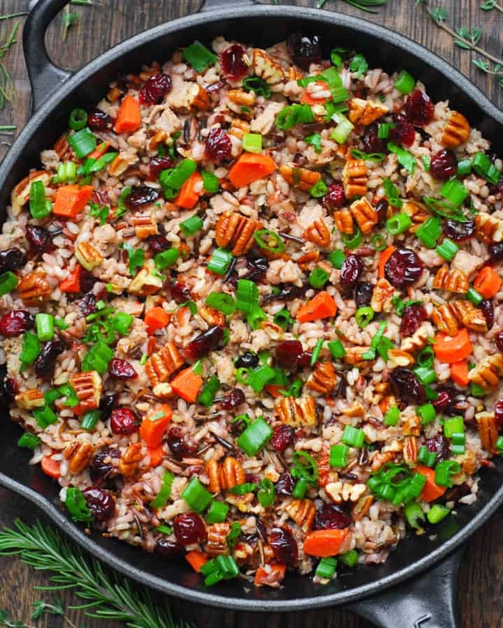 wild rice pilaf with pecans, dried cranberries, carrots, and sausage in a cast-iron pan