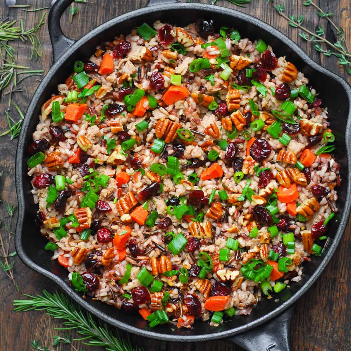 wild rice pilaf with pecans, dried cranberries, carrots, and sausage in a cast-iron pan