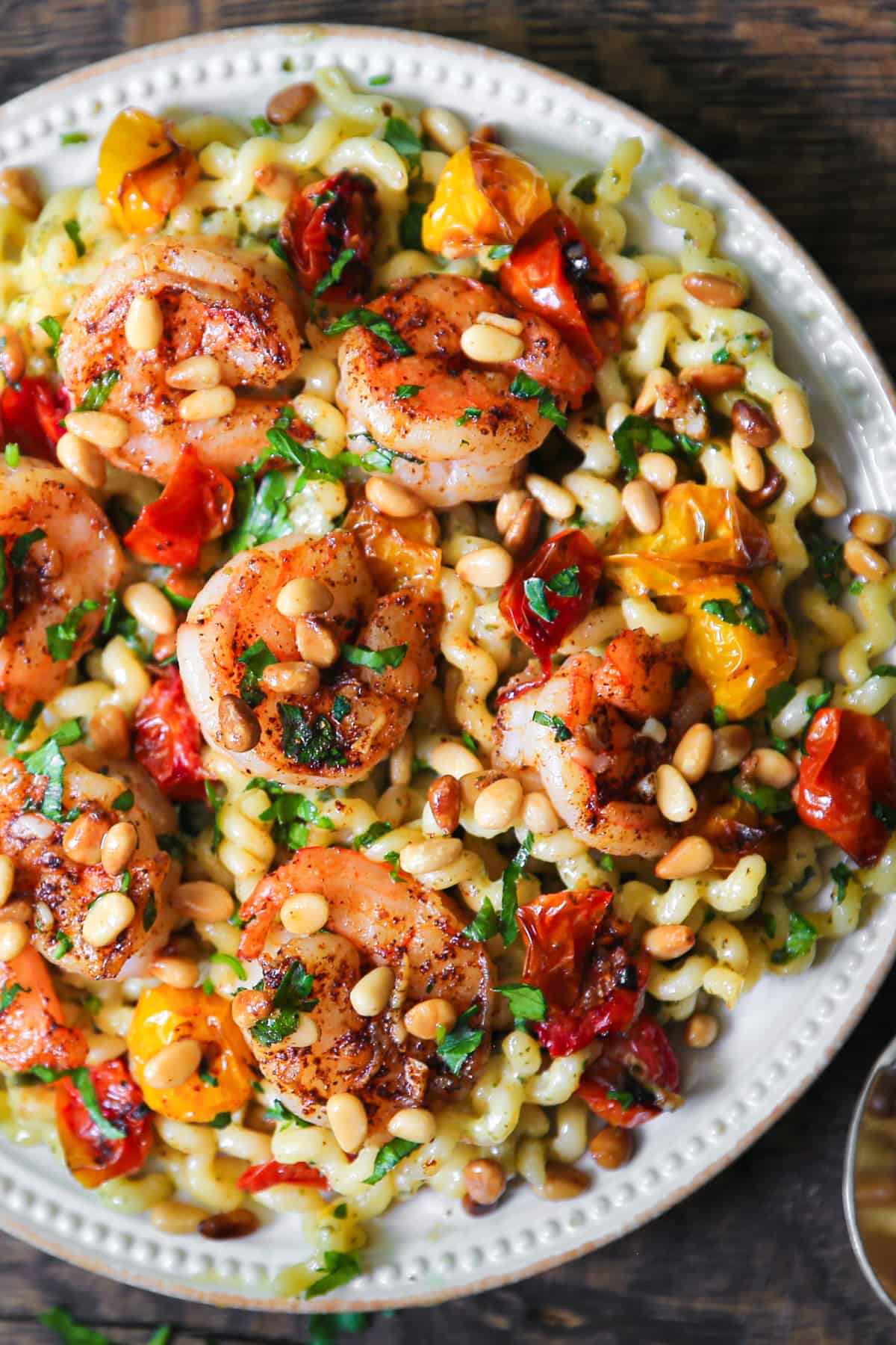 shrimp pesto pasta with roasted cherry tomatoes and pine nuts on a plate